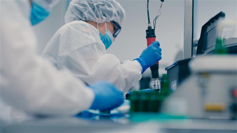 Pharmaceutical technicians in lab coats and gloves compounding medication in FDA-registered facility